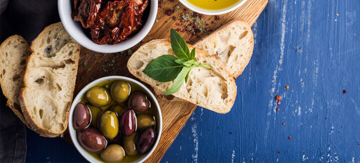 Natürliche Lebensmittel zur Beeinflussung der Hallmarks of Aging: Oliven, getrocknete Tomaten, Olivenöl und Weizenbrot